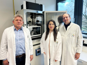 The two corresponding authors Dr Reinhard Viga (left) from UDE and Prof Dr Matthias Gunzer (UDE / ISAS) are standing in front of the ComplexEye microscope with one of the two first authors, PhD student Zülal Cibir.