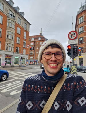 Felix Hormann steht an einer Straßenkreuzung. Im Hintergrund ist ein Verkehrsschild mit dänischer Aufschrift zu sehen.